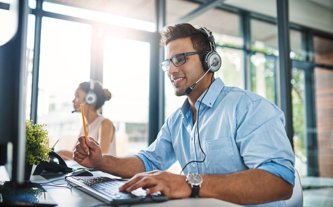 Customer Service Representative wearing a blue shirt while smiling and talking to a customer