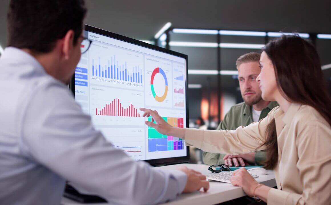 three employees review charts on a monior