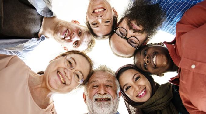 A group of people huddling in a circle smiling for the camera.